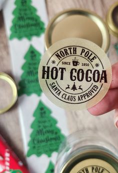 a person holding up a hot cocoa sticker in front of some christmas wrappings