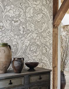 vases and bowls sit on an old dresser in front of a wallpapered background