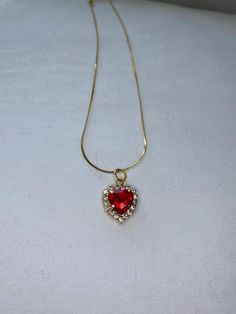 The necklace features a ruby heart pendant on a gold chain. Ruby Heart Necklace, Ruby Heart Pendant, Diamond Heart Necklace, Ruby Heart, Red Diamond, Diamond Heart, Heart Necklace, Pendant Necklaces, Gold Chain