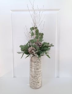 a vase filled with plants and pine cones