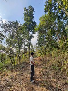 a man standing on a dirt road surrounded by trees