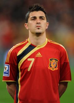 a soccer player is standing on the field with his hands in his pockets and looking off to the side