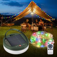 a solar powered light up projector and some people sitting in the grass under a tent