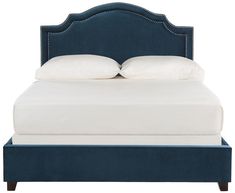 an upholstered bed with white pillows and blue headboard