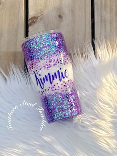 a purple glitter tumbler with the word kimmie on it sitting next to white fur