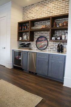 a kitchen with wooden floors and brick wall behind the counter top, built in shelving