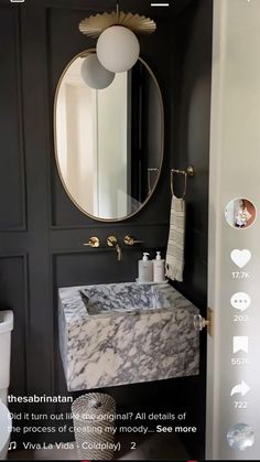 the bathroom is decorated in black and white with marble counter tops, an oval mirror above the sink