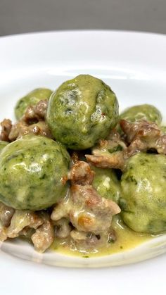 some food is on a white plate with green sauce and meatballs in the middle