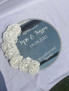 a wedding cake with white roses on it sitting on top of a cloth covered table