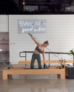 a woman is doing an exercise on a bench in front of a sign that says sweat and good vibes