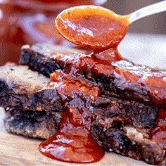 a spoon full of bbq sauce is being held over some meat on a cutting board