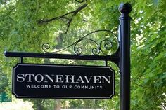 a black and white sign that reads stone haven welcomes you to our community in front of some trees