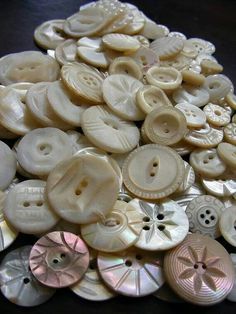 a pile of white buttons sitting on top of a wooden table next to each other