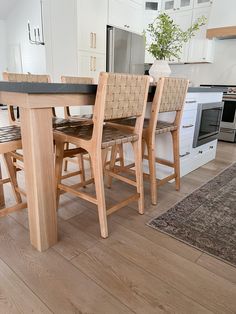 a kitchen table with four chairs and a rug on the floor in front of it