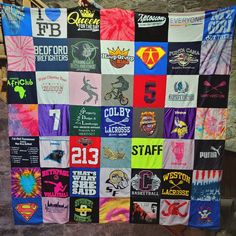 a quilt made out of t - shirts hanging from a clothes line on the side of a building