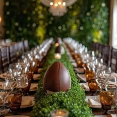 a long table with an arrangement of greenery and a football centerpiece on it