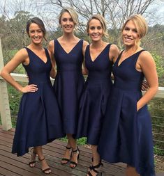 three women in blue dresses standing on a deck with their arms around each other and smiling at the camera