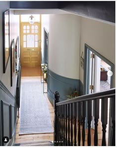 an entry way leading to a yellow door and white walls with black handrails