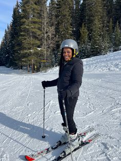 a man riding skis on top of a snow covered slope with trees in the background