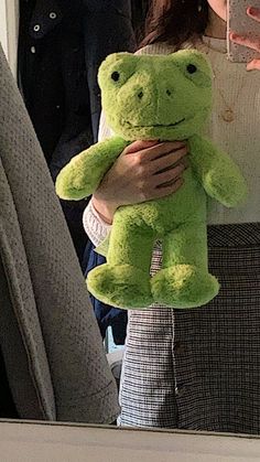 a woman holding a green teddy bear in her arms