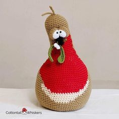 a crocheted stuffed animal in a red dress sitting on top of a table