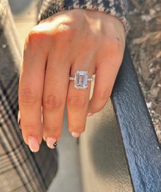 a close up of a person's hand with a diamond ring on their finger