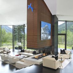 a large living room with high ceilings and floor to ceiling windows overlooking the mountain range