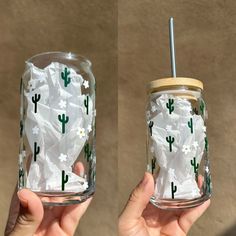 two handmade glass tumblers with white flowers and cactus on them, one is filled with shredded paper