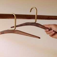 a person is holding two wooden clothes hangers