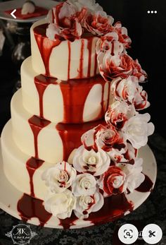 a three tiered cake with red and white icing on the top, decorated with flowers