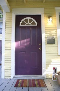 a purple front door on a house with white trim and wood flooring next to it