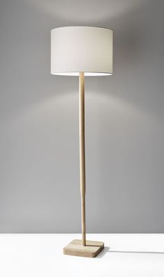 a lamp that is sitting on top of a table with a white shade over it