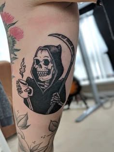 a person with a tattoo on their leg that has a skull holding a coffee cup