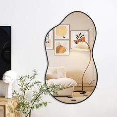 a mirror reflecting a living room with white furniture and art on the wall behind it