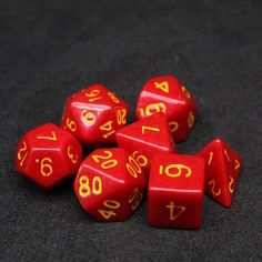 six red dice with yellow numbers on them sitting on a black tableclothed surface