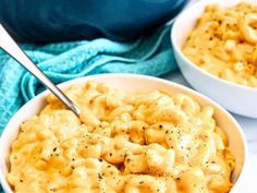 two bowls filled with macaroni and cheese on top of a white tablecloth