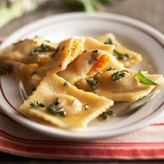 a white plate topped with ravioli on top of a red and white table cloth