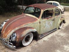 an old rusty car with graffiti on it's side parked in a parking lot