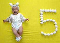 a baby laying on top of a yellow surface next to the letters e and f