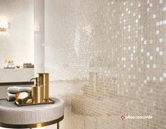 a bathroom with white and gold tiles on the wall, toiletries and soap dispenser