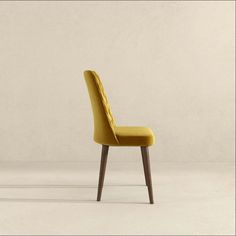 an upholstered yellow chair with wooden legs and back rests against a plain white wall