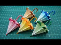 four different colored umbrellas sitting on top of a green table next to each other