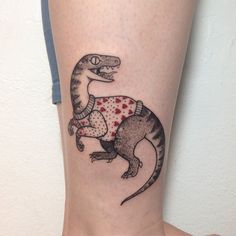 a small tattoo of a dinosaur with a sweater on it's back leg,