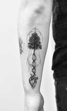 a man's arm with a tree and heart tattoo on it