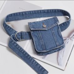 a blue jean bag with a white bow on the side and a card holder attached to it