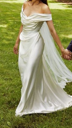 a bride and groom holding hands in the grass