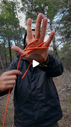 a man is holding his hand up to the camera with an orange string attached to it