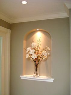 a vase filled with flowers sitting on top of a white shelf next to a doorway