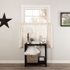 a room with white walls and wooden flooring has a black star hanging on the wall