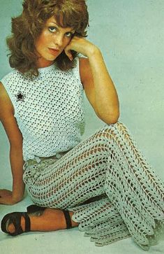 a woman sitting on the ground wearing white crocheted clothing and sandals with her hand under her chin